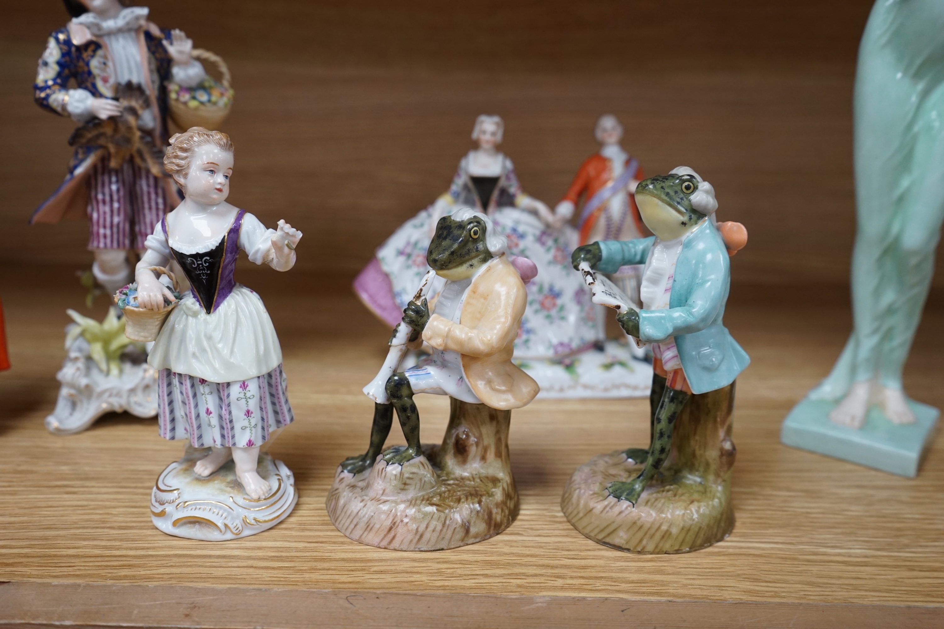 Eight Royal Doulton and 19th century German figures, including two Sitzendorf frog musicians, a Royal Doulton Celia (HN1727) and the toy seller. Condition - fair to good, substantial cracks and damage to the Celia figure